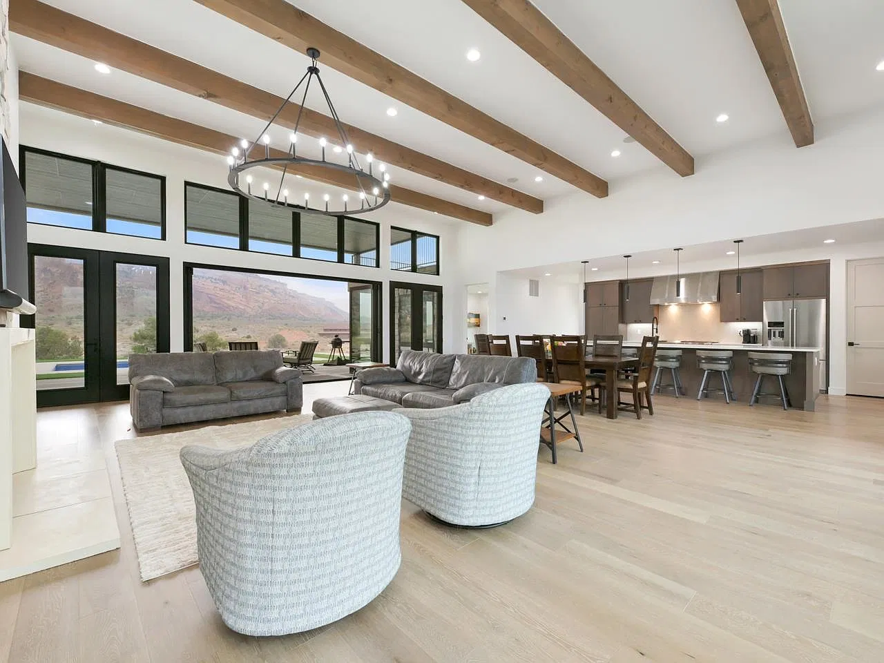 Open living room with wood ceiling beams, chandelier and kitchen beyond