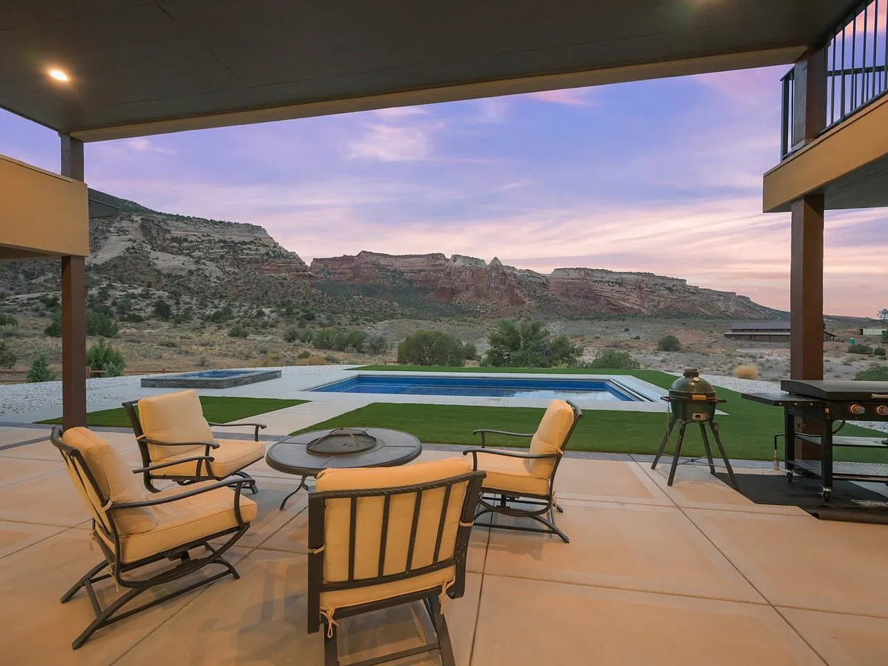 Covered patio at dusk looking out over the pool and red rock cliffs